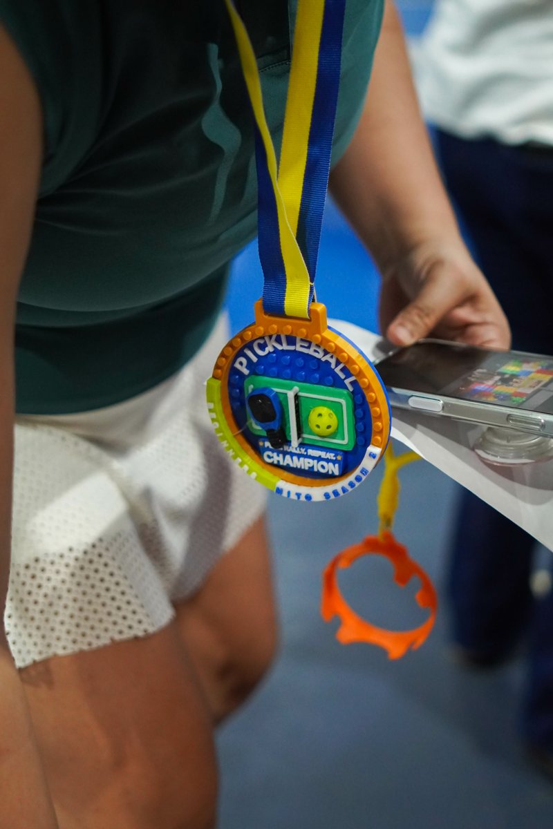 A multi-color 3D printed pickleball champion medal hanging on a blue and yellow ribbon, worn by a player at a tournament in Davao City.