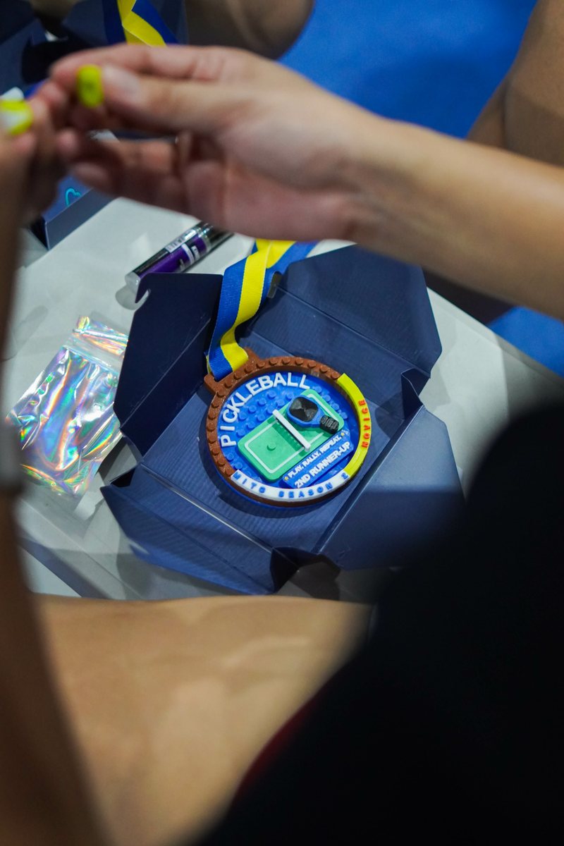 A multi-color 3D printed medal resting inside an opened navy gift box, ready to be given away as a personalized award.